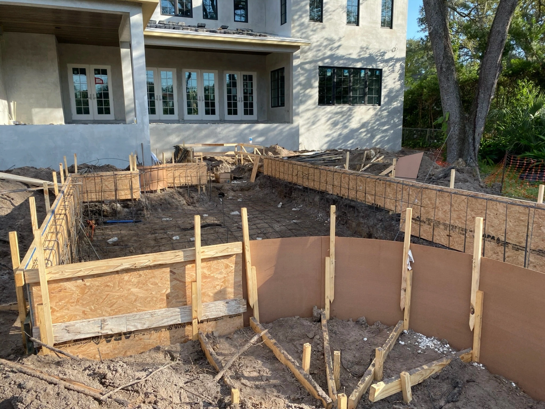 Pool excavation and rebar forming in progress at a custom home construction site